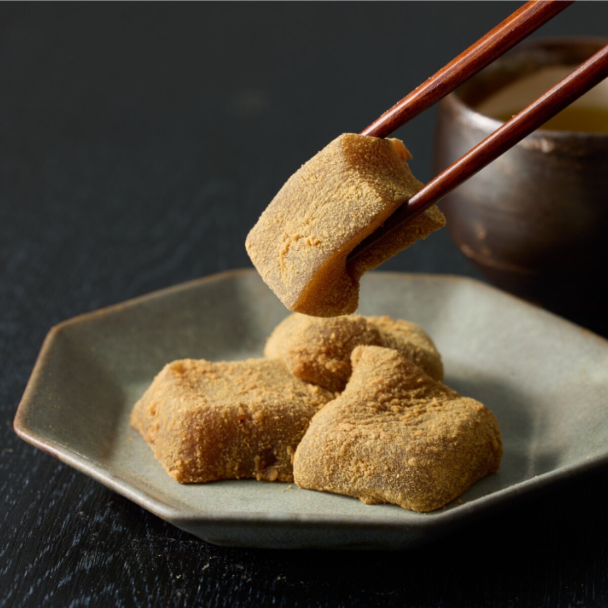 箸でつまみ上げた、きな粉をまとう生わらび餅